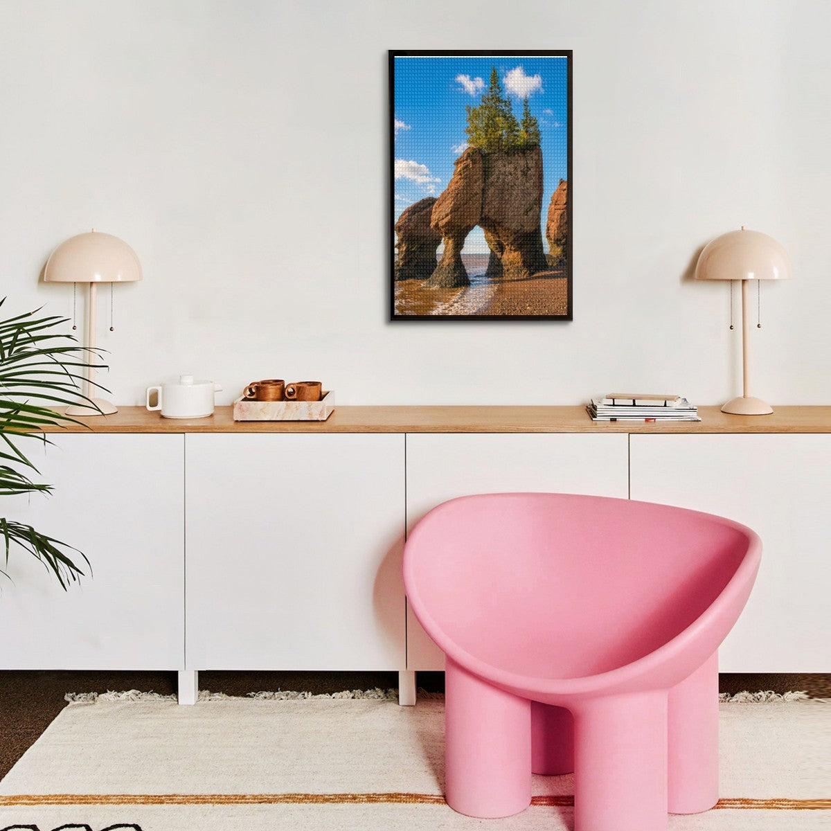 Modern interior with a pink chair, wooden desk, and framed picture on the wall.