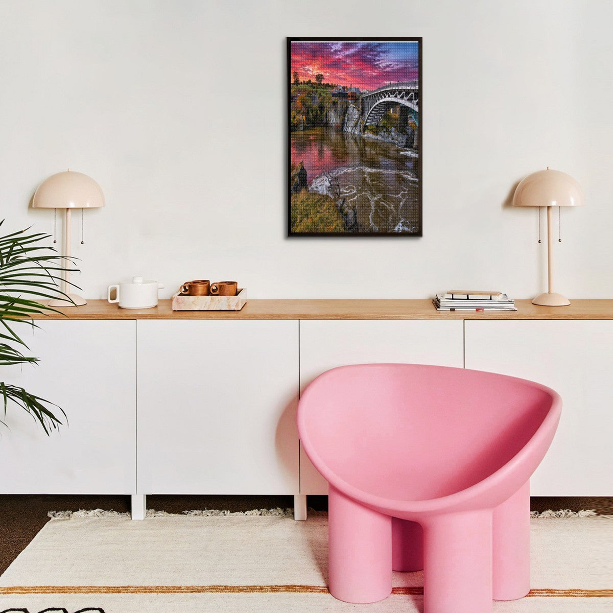 Modern interior with a pink chair, wooden desk, and framed artwork on the wall.